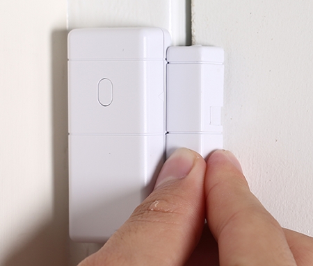 A person mounting the door sensor on the wall A person mounting the door sensor on the wall