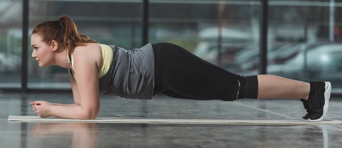 A woman in a ponytail holding her body in plank position