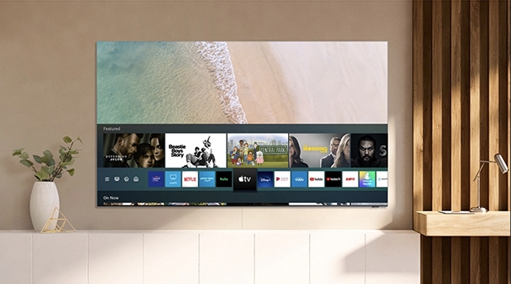 Samsung Smart TV hangs on the wall displaying the Apple TV app, with access to Apple TV + content.