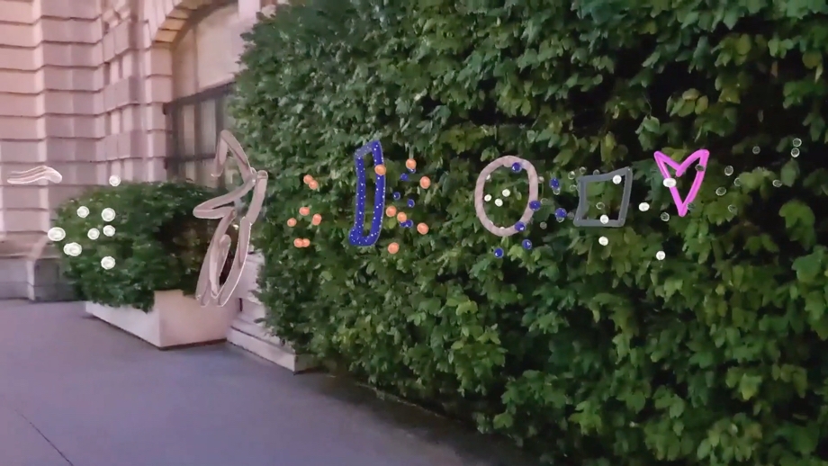 A video still of polka dots, a star, circle, square and heart AR doodles against a backdrop of greenery