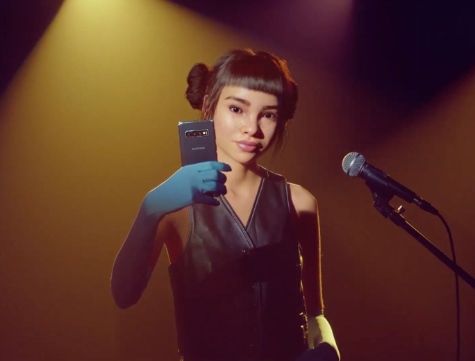Miquela taking a selfie on a Galaxy S10 as she stands under a spotlight and in front of a microphone