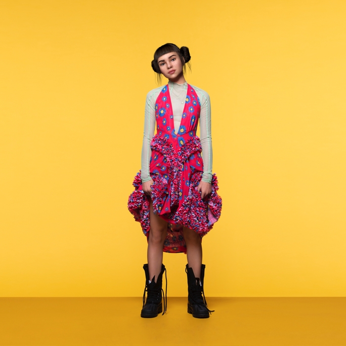 A full-body, promotional shot of Lil Miquela wearing a brightly colored dress while looking confidently into the camera