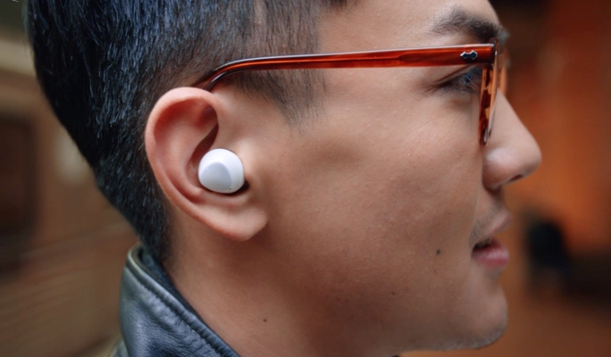 A profile shot of a man wearing a white Galaxy Buds+ earbud in his right ear
