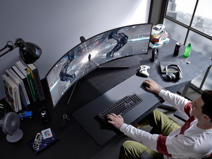 Overhead shot of a man at a desk gaming on a curved monitor