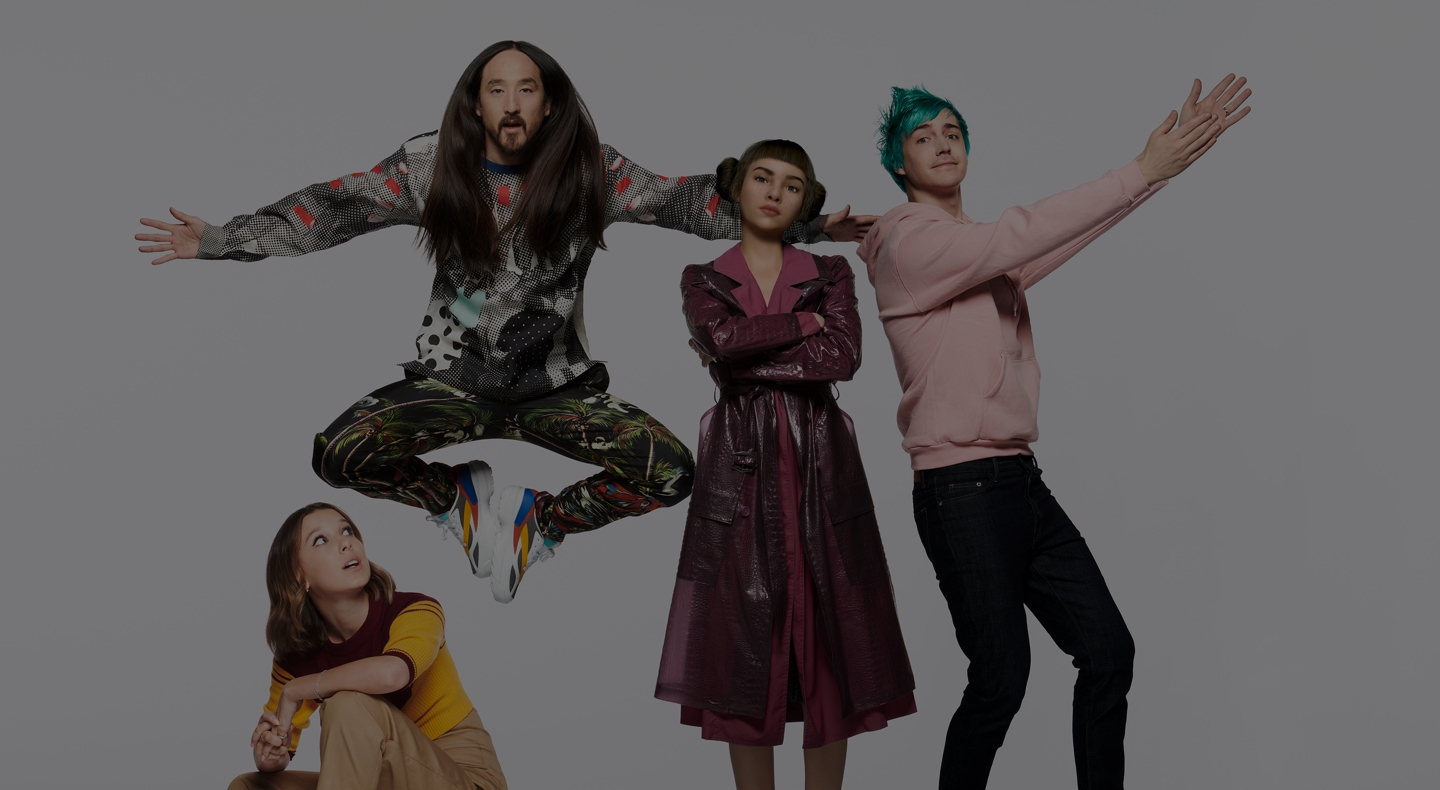 #TeamGalaxy group photo featuring (LTR): Millie Bobby Brown crouching down in white heels as she looks upward to her right, Steve Aoki posing in mid-air with his arms outstretched and feet facing each other inwards, Lil' Miquela stands tall as she folds her arms across her chest and looks confidently straight ahead, Ninja sporting a pink hoodie as he extends his arms to the right side and stands with his left foot pointing outwards.