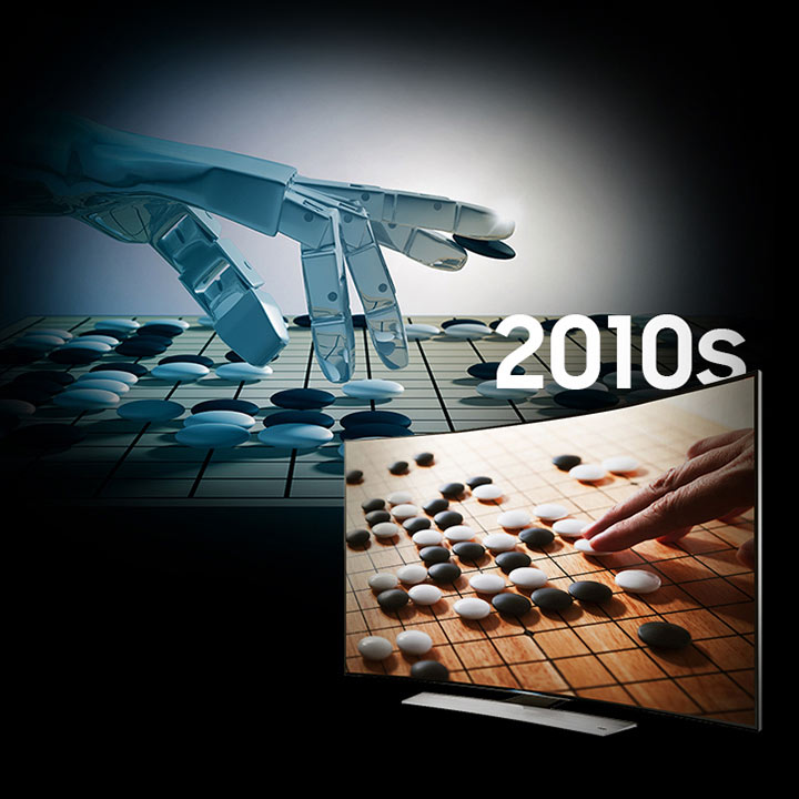 background image of a robot hand playing a game of Go. On the screen of a curved television screen is a go board with a person’s hand poised to make a move.