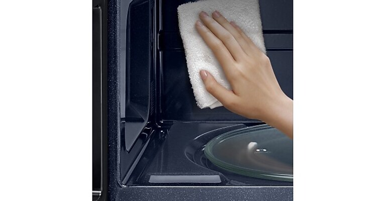 Person using cloth to clean inside of a Samsung Microwave Person using cloth to clean inside of a Samsung Microwave