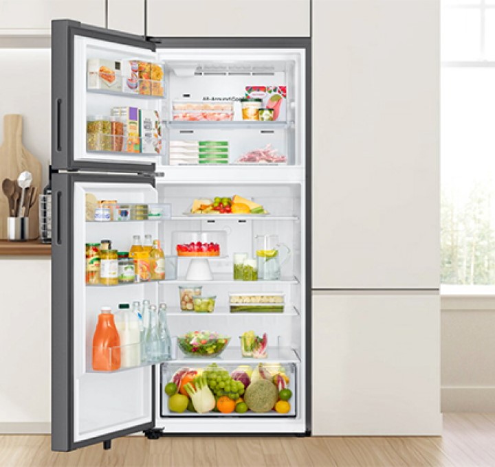 Stainless steel top freezer refrigerator with doors open and fully stocked in modern kitchen Stainless steel top freezer refrigerator with doors open and fully stocked in modern kitchen
