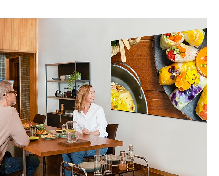 This is an image to demonstrate the amount of color QLED 8K can express in comparison to conventional TVs. A couple is admiring the crisp details and colors of the 8K as they watch food recipe videos shot with Galaxy S20, shown on QLED 8K.