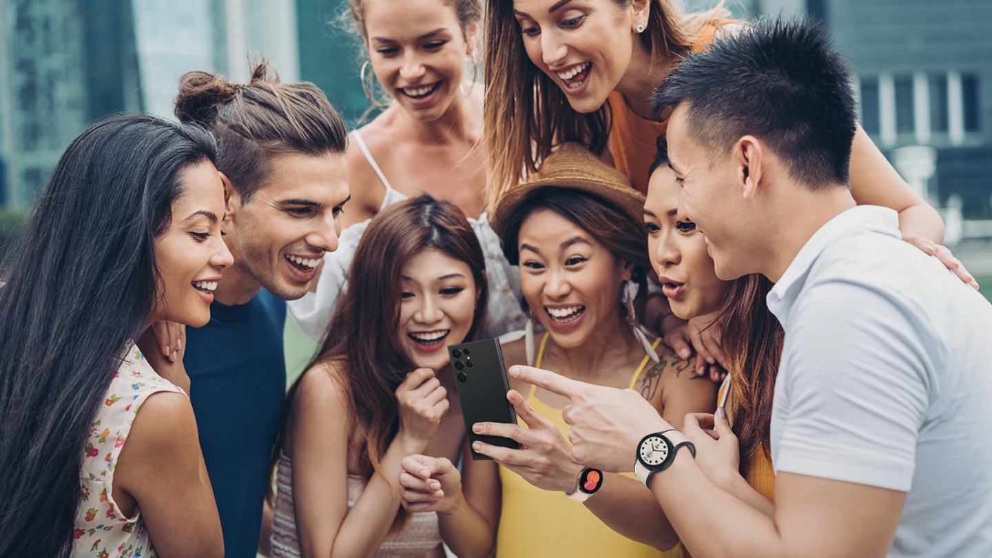 Five mixed adults of a multi-racial race are enjoying watching their cell phones.