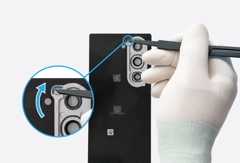 Gloved hands removing the double-sided adhesive tape around the microphone hole from the Galaxy Z Fold6.