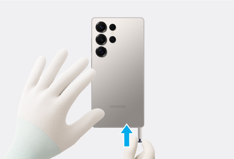 Gloved hands inserting the S Pen into the bottom slot of the Galaxy S25 Ultra.