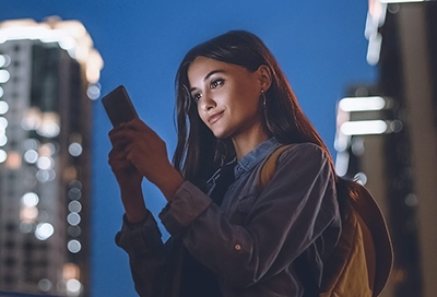 Girl holding phone with city in the background Girl holding phone with city in the background