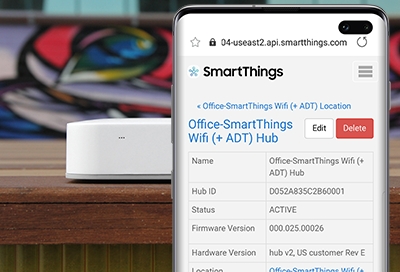 SmartThings Hub next to a Galaxy phone displaying Hub details SmartThings Hub next to a Galaxy phone displaying Hub details