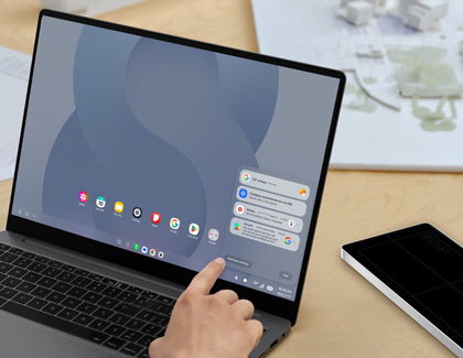 A person touching a laptop screen in Samsung DeX mode showing a list of notifications for weather charging and emails in the bottom right corner.