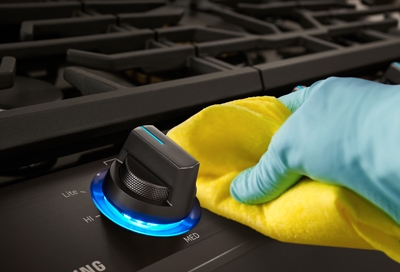 Person cleaning the knobs of Samsung gas cooktop