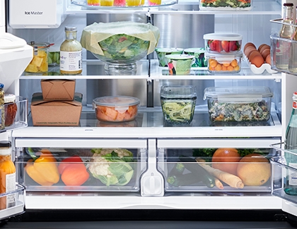 Lower shelves of a Samsung Fridge with eggs, salad, vegetables, and containers of leftovers