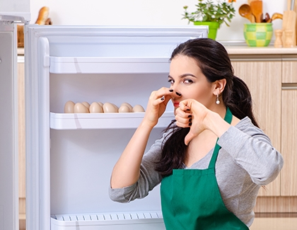 Woman smelling a bad odor in the fridge