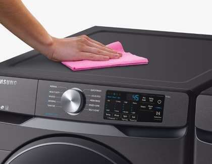 Person cleaning washer surface with microfiber cloth