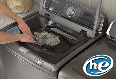 Washing clothes in top load washer with HE detergent logo