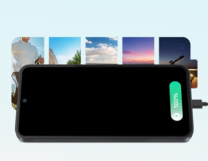 A Galaxy phone lying horizontally and charging with a green battery status indicating 100 percent, with a sequence of scenic photos behind it.