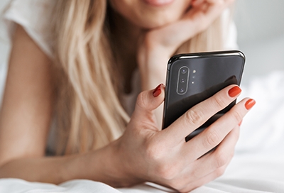 Girl with red nail polish smiling at phone Girl with red nail polish smiling at phone