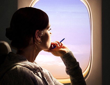 A woman looking out a plane window with S Pen in her hand A woman looking out a plane window with S Pen in her hand