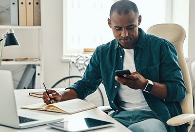 Guy looking at phone while writing Guy looking at phone while writing