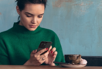 Girl using phone while drinking coffee