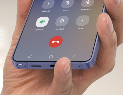 A hand holding a Samsung Galaxy phone with a finger covering the bottom microphone.