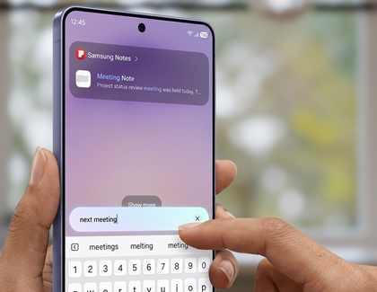 Hands holding a Galaxy S26 Ultra typing next meeting into the Finder search bar with a Samsung Notes result displayed above.