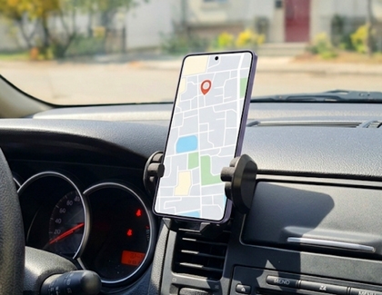 A Galaxy phone displaying a navigation map application while mounted on a dashboard phone holder inside a car.
