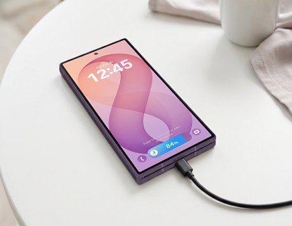 A purple Galaxy Z Fold8 Ultra displayed on a white table showing the lock screen with a charger connected at the bottom.