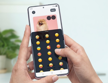 Hands holding a pink Galaxy Z Flip8 selecting an emoji to edit a photo of a small dog.