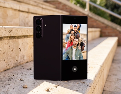 A Galaxy Z Fold8 Ultra on steps showing a group photo preview on its cover screen.