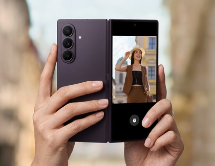 Hands holding a Galaxy Z Fold8 Ultra showing a camera preview on its cover screen.