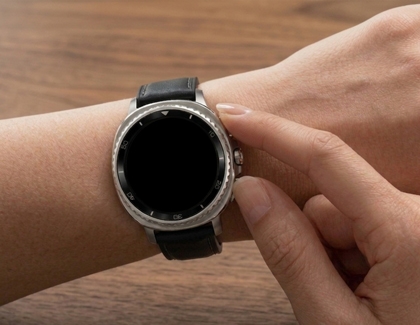 A close up of a person pressing the top side button on a Galaxy Watch.