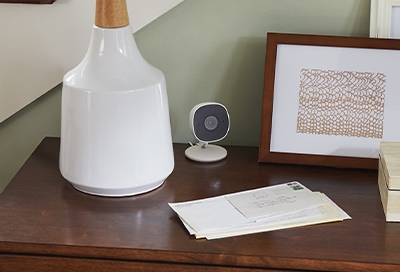A Smart Cam on a table next to a lamp A Smart Cam on a table next to a lamp
