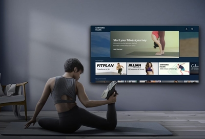 Woman stretching with Samsung Health app displayed on a Samsung TV