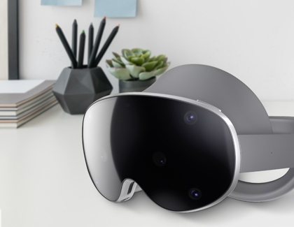 Galaxy XR headset placed on a desk beside a plant and stationery.