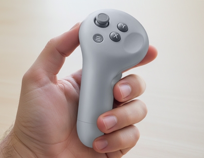 Hand holding a Galaxy XR controller showing the buttons and joystick.
