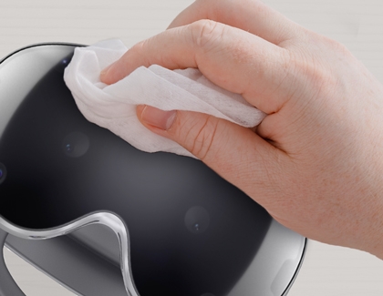 Hand wiping the lens area of a Galaxy XR headset with a soft cloth.