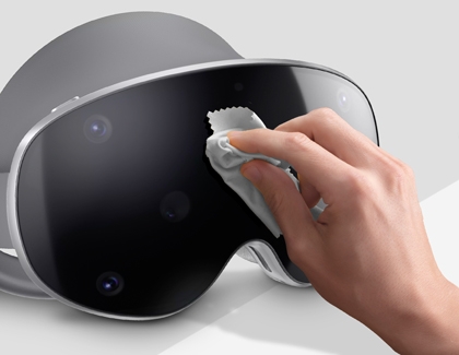 Hand wiping the lens area of a Galaxy XR headset with a microfiber cloth.