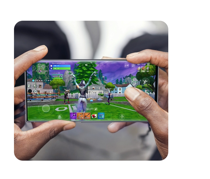 Close up pair of hands holding a Galaxy 5G phone in landscape orientation playing Fortnite. 