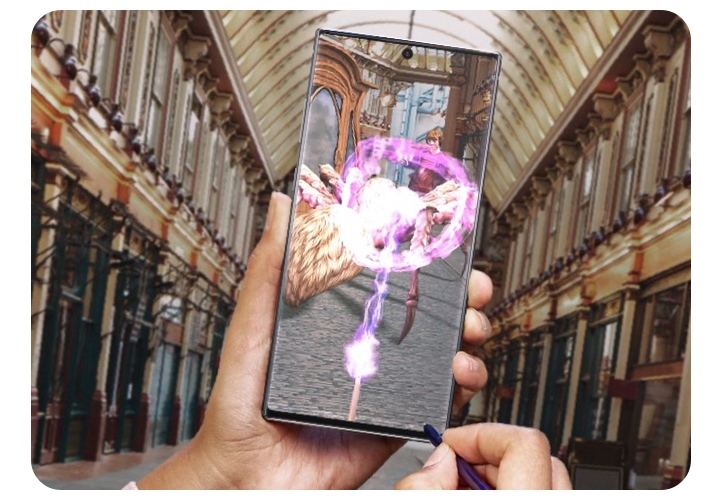 The image shows a cropped image of a person's hands while they are playing an augmented reality game on the Galaxy Note10 with the included pen. 