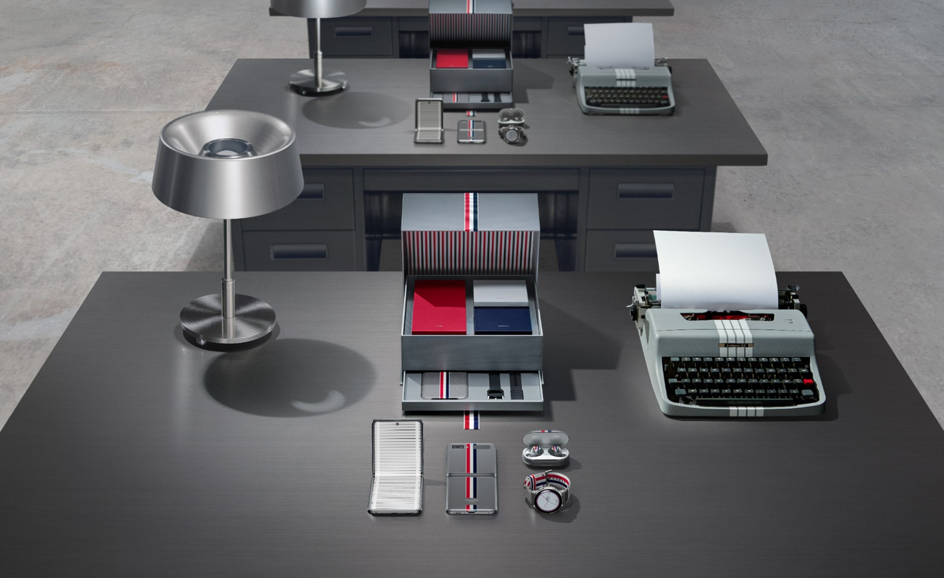 Galaxy Z Flip Thom Browne Edition, showing the collection on a desktop with a typewriter and a steel lamp. The package is opened to reveal the drawers inside, showing the special edition Galaxy Z Flip, Galaxy Buds plus, Galaxy Watch Active2, Leather Cover, and Galaxy Watch Active2 straps