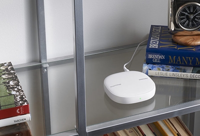 A SmartThings Wifi Hub sitting on a glass shelf