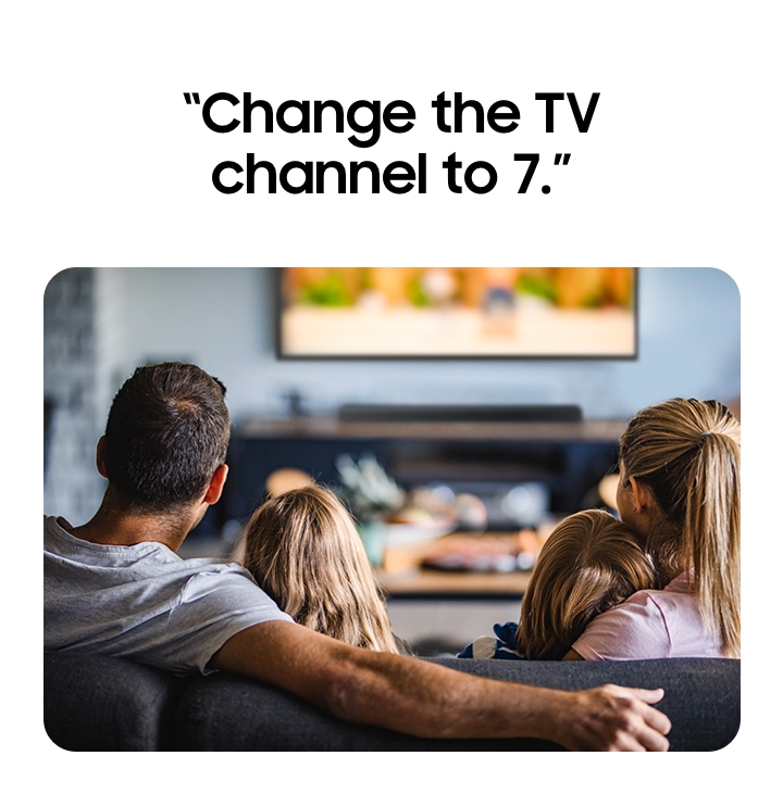 A family sitting on a sofa, watching TV.