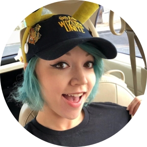 A headshot of Holly Patterson sporting a black baseball cap as she sits in a car. Her mouth is slightly ajar.