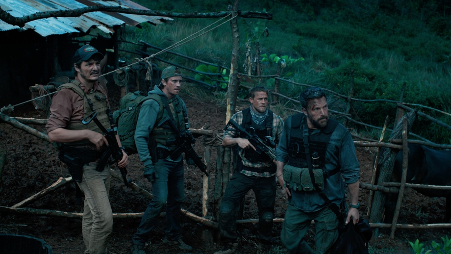 Scene from Netflix Originals movie Triple Frontier via Netflix mobile app that shows four, armed ex-US Special Forces soldiers wearing bullet-proof vests while standing in what looks like a field